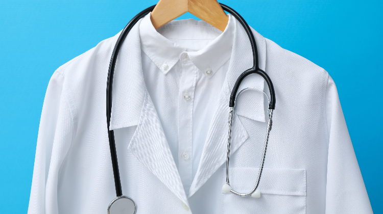 Jaleco branco com estetoscópio ilustra o debate sobre o ENAMED obrigatório para exercer a medicina no Brasil.
